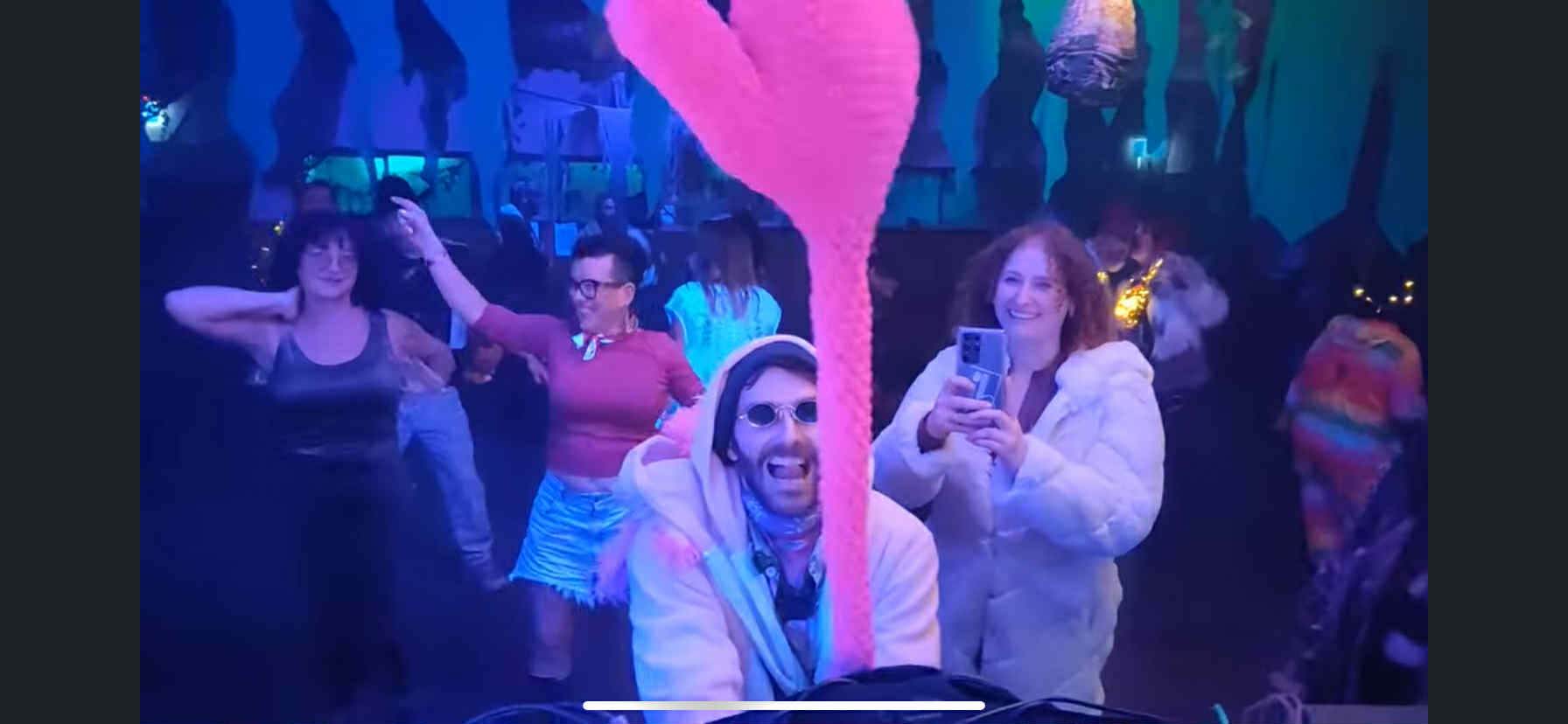 People dancing with arms raised in joy at Third Degree Burn, bathed in vibrant pink and blue lighting, capturing the magical Sunday night moment described in the text